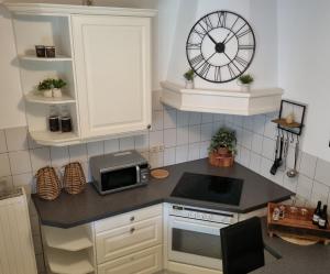 a kitchen with a microwave and a clock on the wall at Hotel Restaurant Keizersberg in Elsendorp