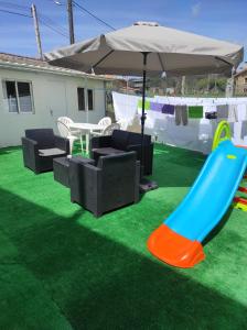 a playground with a slide and an umbrella at Albergue La Corona1 in O Pino 