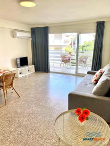 a living room with a couch and a table with flowers on it at APARTBEACH DIANA Vistas Playa y Climatizado in Salou
