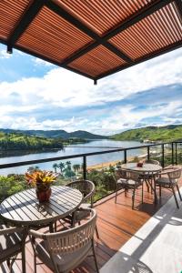 a deck with tables and chairs and a view of a river at Vista do Lago Hotel in Capitólio