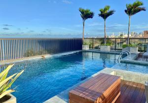 a swimming pool with a wooden bench next to a building at ARPOAR - Manaíra by PenareiaTurBr in João Pessoa