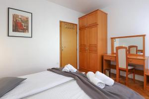 1 dormitorio con escritorio y 1 cama con almohadas blancas en Apartments Villa Bernarda, en Šilo