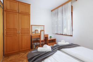 a bedroom with a bed and a desk with a mirror at Apartments Villa Bernarda in Šilo