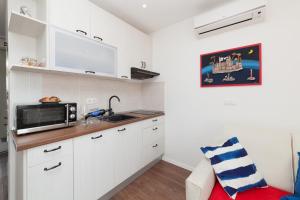 uma cozinha com armários brancos e um micro-ondas em Imperium Central Apartments Zadar em Zadar