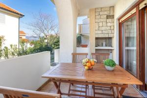 ein Holztisch mit Obst auf einem Balkon in der Unterkunft Apartments Villa Bernarda in Šilo