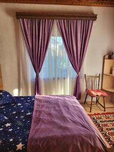 a bedroom with a purple bed and a window at Casa Roza in Breaza de Sus