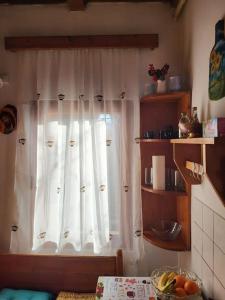 une cuisine avec une fenêtre dotée d'un rideau blanc dans l'établissement Casa Roza, à Breaza de Sus