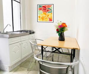 a kitchen with a table with a vase of flowers on it at Hotel Amigo Suites in Mexico City