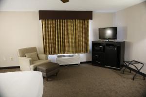 Habitación de hotel con cama, TV y silla en Baymont by Wyndham Rockford, en Rockford