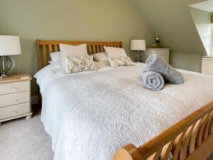 una camera da letto con un grande letto bianco con cuscini di The Bothy a Lymington