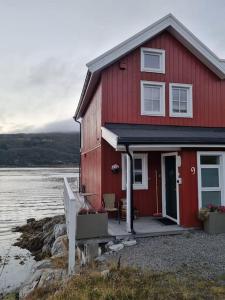 una casa roja en la orilla de un cuerpo de agua en Sjøhus ved Tjeldsundet - House by the sea, en Evenskjer