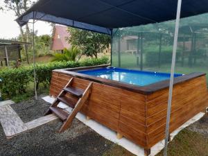 a hot tub with an umbrella and a chair at Chava Camping Rio Celeste in Rio Celeste