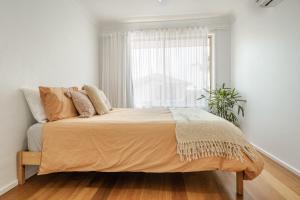 a bed in a white bedroom with a window at Lennox Beach Oasis 3 Bedrooms in town in Lennox Head