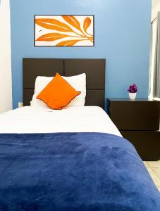 a bedroom with a bed with an orange pillow at Hotel Amigo Suites in Mexico City