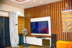 a living room with a flat screen tv and a fan at Superb 2-Bedroom Duplex FAST WiFi+24Hrs Power in Lagos