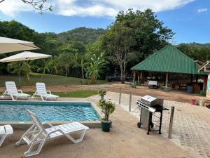 een zwembad met een grill en stoelen en een piano bij Casa Cooper in Carrillo