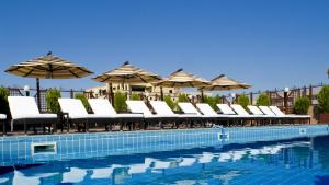 una fila de sillas y sombrillas junto a una piscina en Grand Hotel Yerevan - Small Luxury Hotels of the World en Ereván