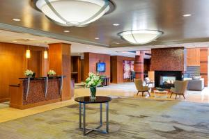 Courtyard by Marriott Boston Logan Airport في بوسطن: لوبي فندق مع إناء ورد على طاولة