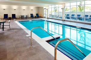 a pool in a hotel with tables and chairs at TownePlace Suites by Marriott Columbus Easton Area in Columbus