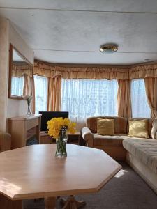 a living room with a table and a couch at Rhosfeillion Static Caravan in Llangefni