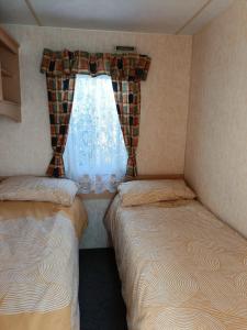two beds in a small room with a window at Rhosfeillion Static Caravan in Llangefni