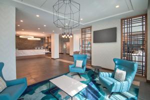 a lobby with blue chairs and a table and a television at TownePlace Suites by Marriott Miami Airport in Miami