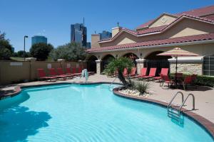 TownePlace Suites Fort Worth Downtown في فورت وورث: مسبح كبير مع كراسي ومظلات