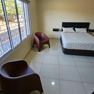 a bedroom with a bed and a chair and windows at Mensú Grand Hotel in Puerto Iguazú