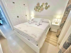 Una cama blanca en un dormitorio blanco con una lámpara de araña. en Sunset Seaview La Arena en Puerto de Santiago