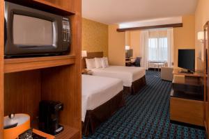 a hotel room with two beds and a tv at Fairfield By Marriott Huntington in Huntington