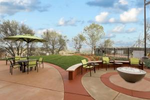 eine Terrasse mit Tischen, Stühlen und einem Sonnenschirm in der Unterkunft SpringHill Suites by Marriott Auburn in Auburn