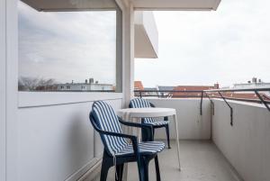 einen Balkon mit 2 Stühlen, einem Tisch und einem Fenster in der Unterkunft Haus Hanseatic, Wohnung 302 in Duhnen