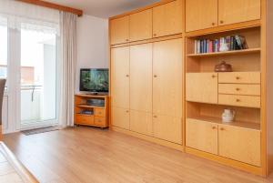 ein Wohnzimmer mit Holzschränken und einem TV in der Unterkunft Haus Hanseatic, Wohnung 302 in Duhnen