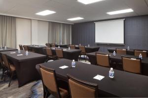 Fairfield Inn & Suites by Marriott Charleston في تشارلستون: قاعة اجتماعات مع طاولات وكراسي وشاشة بيضاء