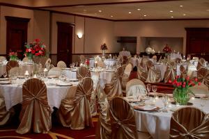 un salón de banquetes con mesas y sillas blancas en Marriott Cincinnati North, en West Chester