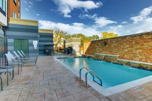 uma piscina com cadeiras e uma parede de tijolos em Fairfield Inn and Suites by Marriott Houston Brookhollow em Houston