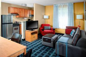 a living room with a couch and a tv and a kitchen at TownePlace Suites Fresno in Fresno