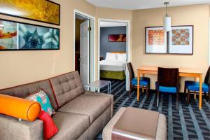 TownePlace Suites Fresno في فريسنو: غرفة معيشة مع أريكة وطاولة وسرير