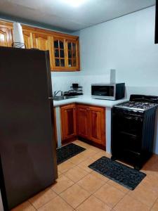 a kitchen with a black refrigerator and wooden cabinets at Comfort Cottage at the Grove in Mandeville