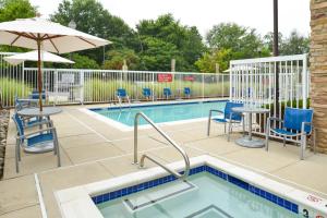 a swimming pool with chairs tables and an umbrella at TownePlace Suites Arundel Mills BWI Airport in Hanover