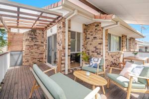 a patio with chairs and tables on a wooden deck at Lennox Beach Oasis 3 Bedrooms in town in Lennox Head