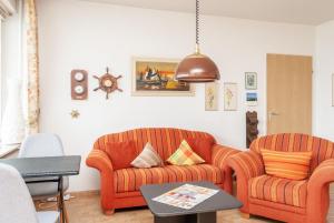 een woonkamer met 2 oranje stoelen en een tafel bij Haus Hanseatic, Wohnung 512 in Duhnen