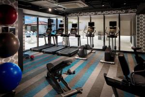 a gym with rows of tread machines and a pool at Aloft Coral Gables in Miami