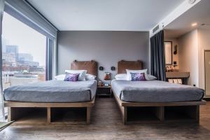 a bedroom with two beds and a large window at Moxy Chicago Downtown in Chicago