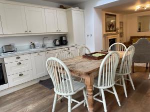 cocina con mesa de madera y sillas blancas en Beautiful 3 Bed Basement Flat With Garden, en Bath