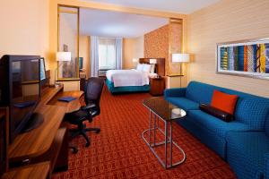 a hotel room with a blue couch and a bed at Fairfield Inn & Suites Houston Hobby Airport in Houston