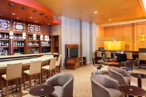 Sheraton LaGuardia East Hotel في كوينز: مطعم به بار به طاولات وكراسي