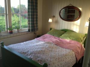 Schlafzimmer mit einem Bett, einem Spiegel und Fenstern in der Unterkunft Droomgaerd in Vlist