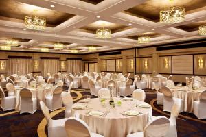 クイーンズにあるSheraton LaGuardia East Hotelの白いテーブルと椅子、シャンデリアが備わる宴会場