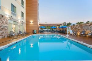 Fairfield Inn & Suites by Marriott Alexandria في أليكساندريا: مسبح كبير مع كراسي ومبنى